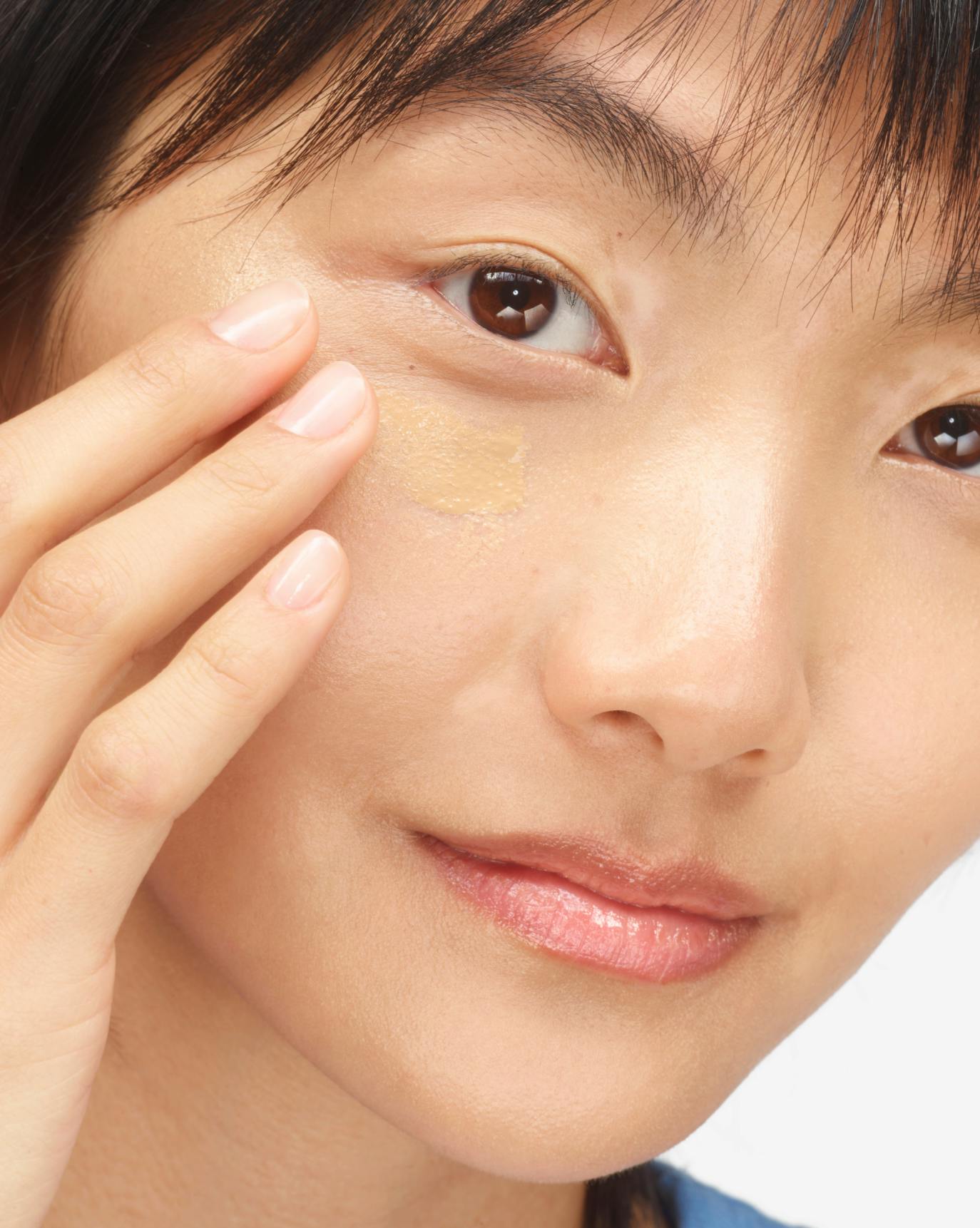 Yoyo applies Stretch Balm Concealer in M1.