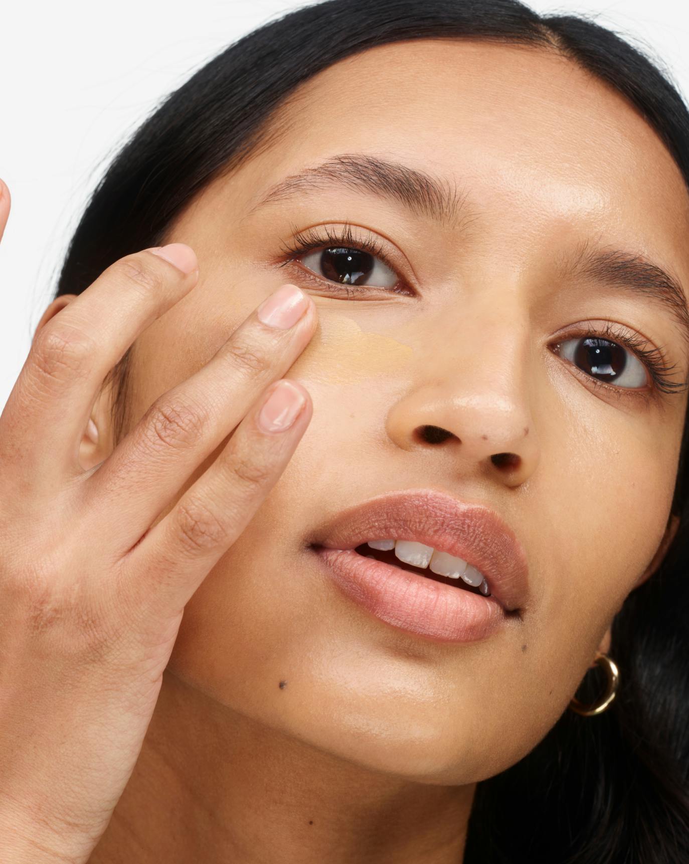 Thasfia applies Stretch Balm Concealer in MT1.