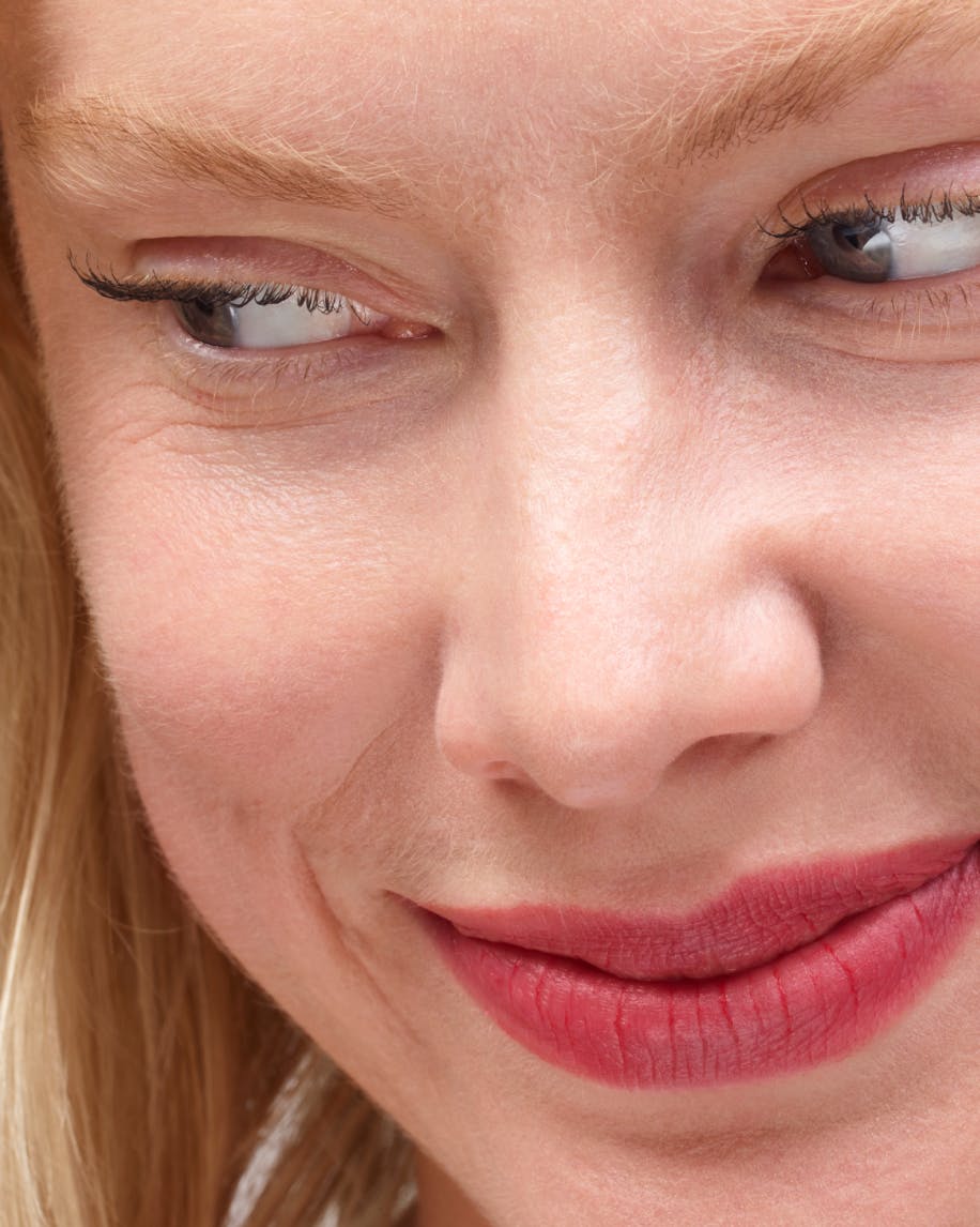 close up of model's face looking down wearing generation g in punch on lips.