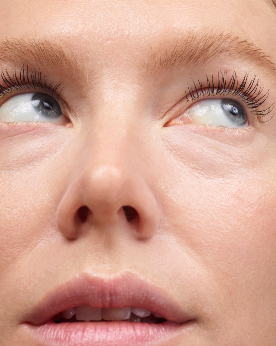 close up of model's face eyes looking up to the right wearing lash slick in black on eyelashes